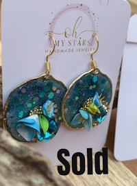 a pair of earrings with a blue flower on them