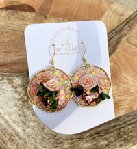 a pair of earrings with pink roses and green leaves